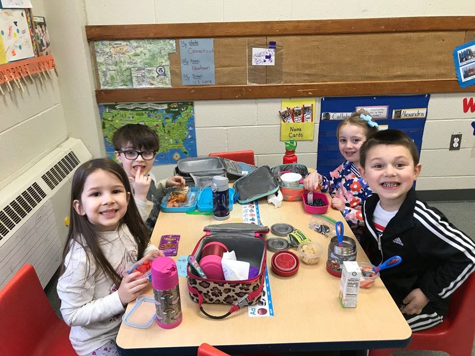 Four children sitting at a table with lunchboxes