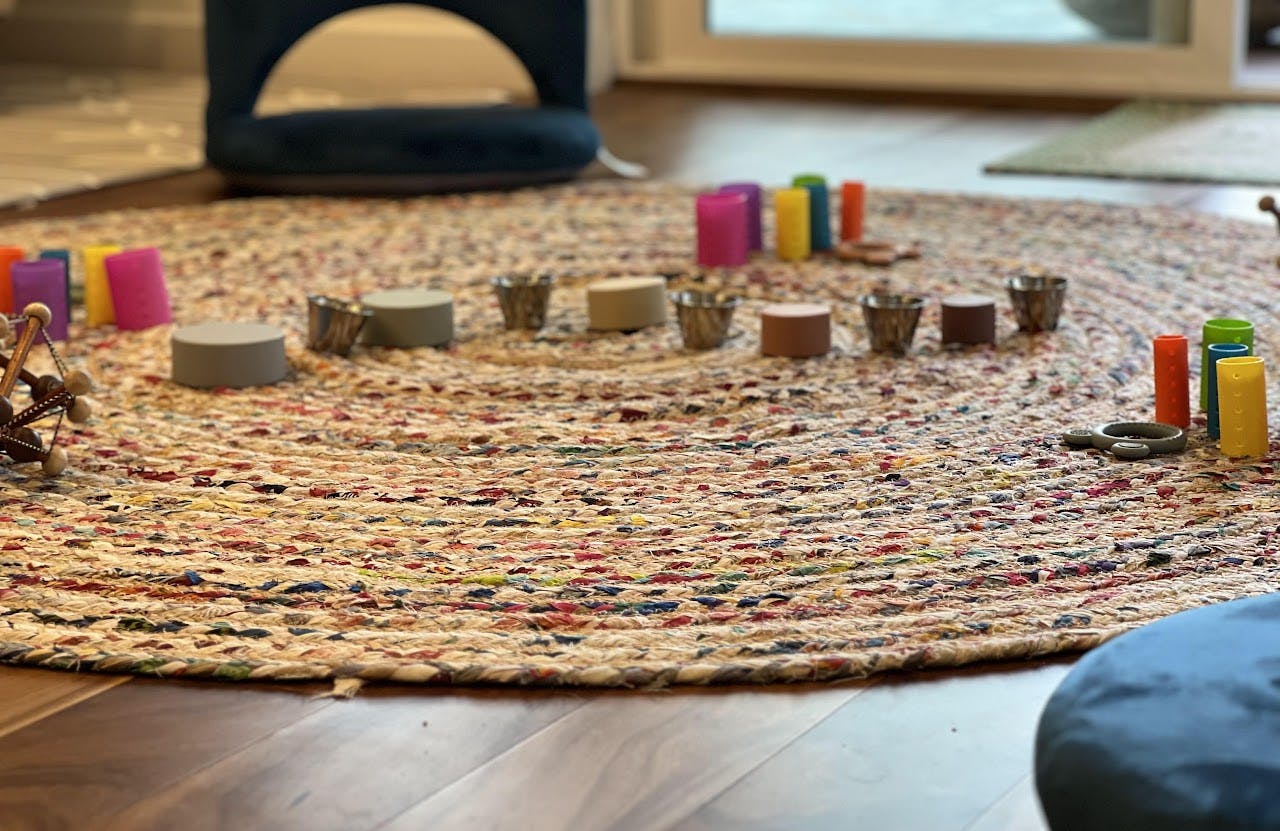 Colorful Montessori toys and small cups on a round braided rug