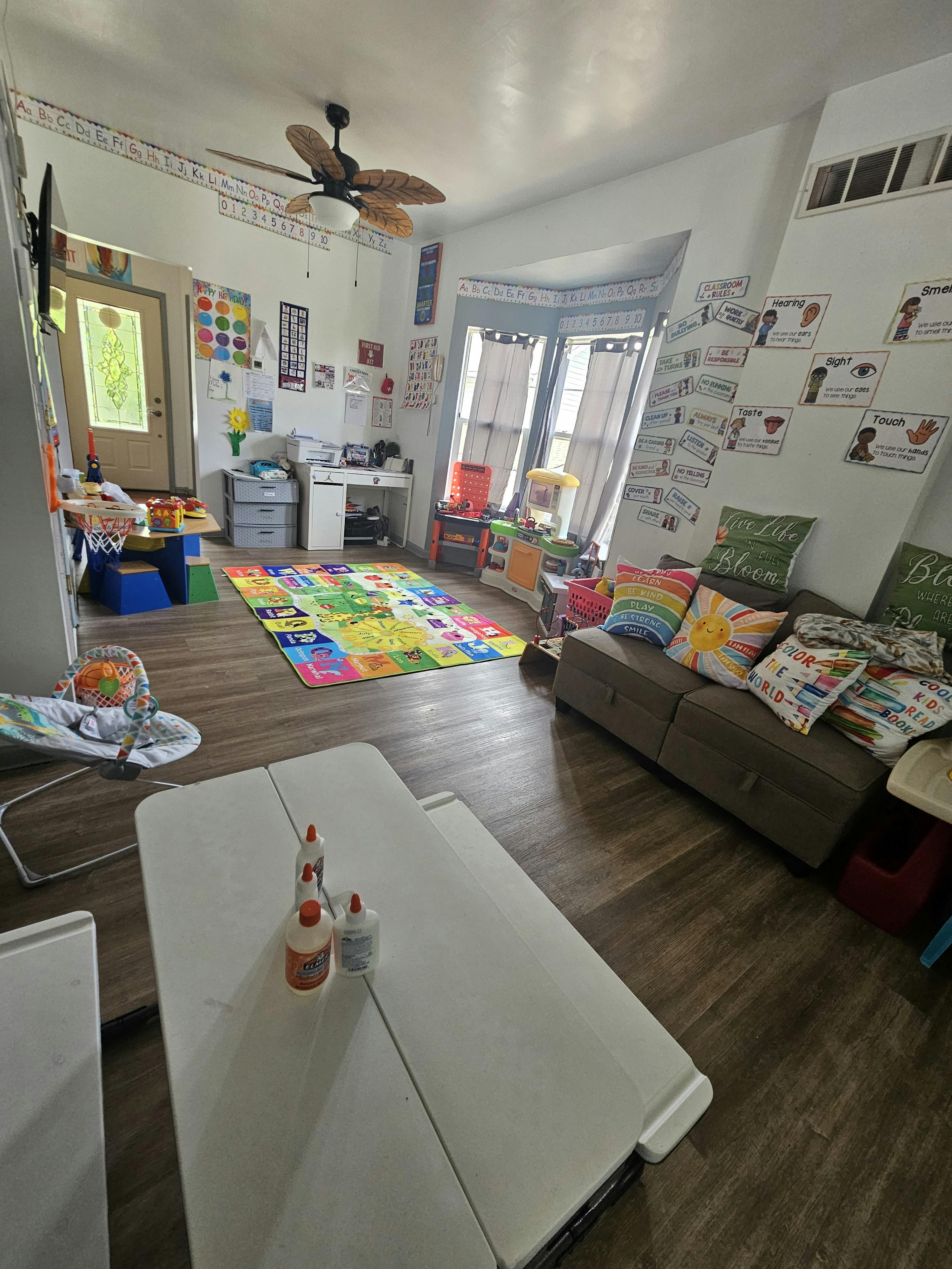 Playroom with colorful rug, sofa, and tables