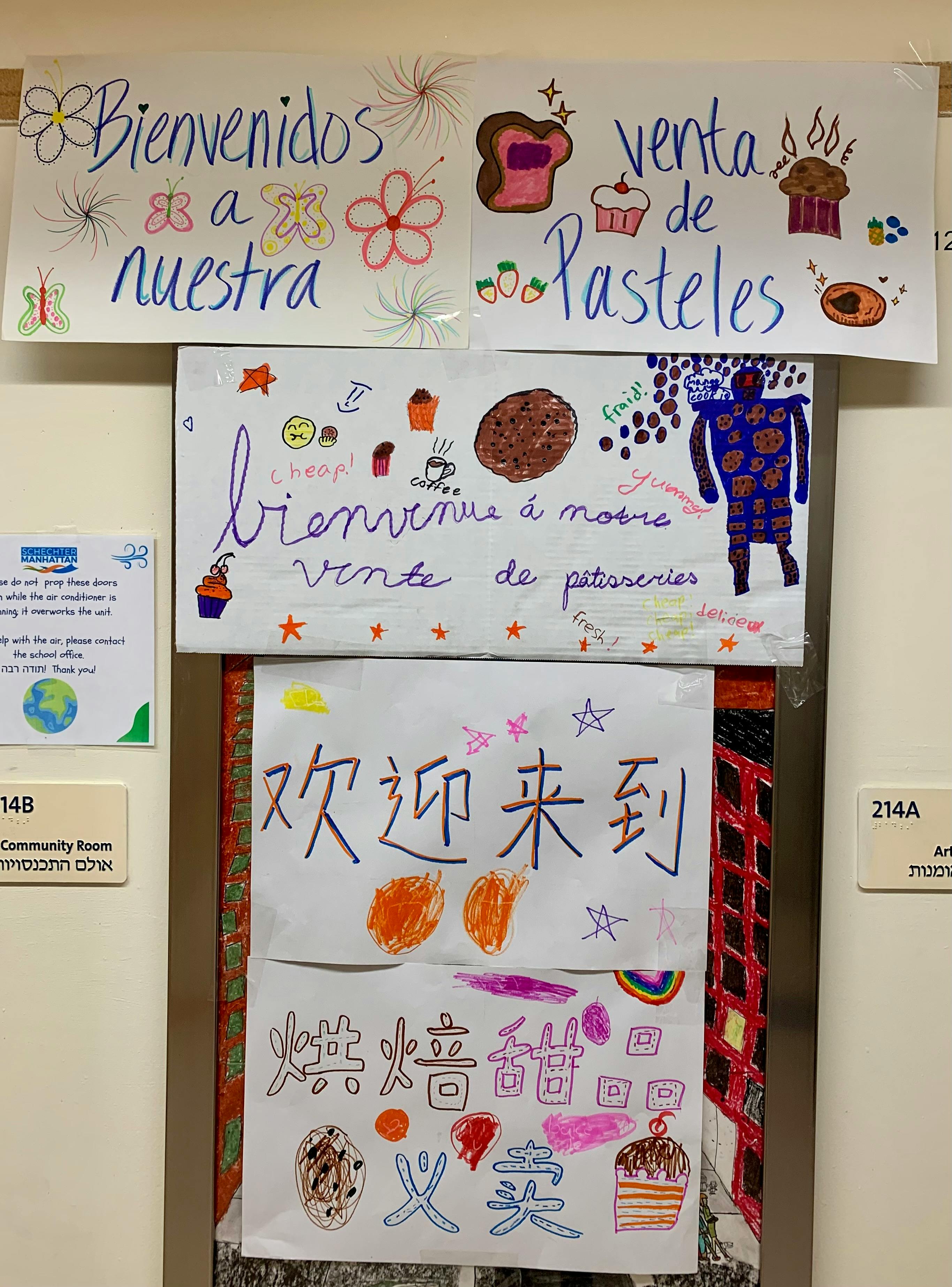 Multilingual signs for a bake sale with drawings of cupcakes and cookies