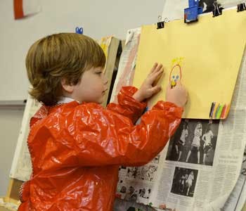 Child in smock drawing on an easel