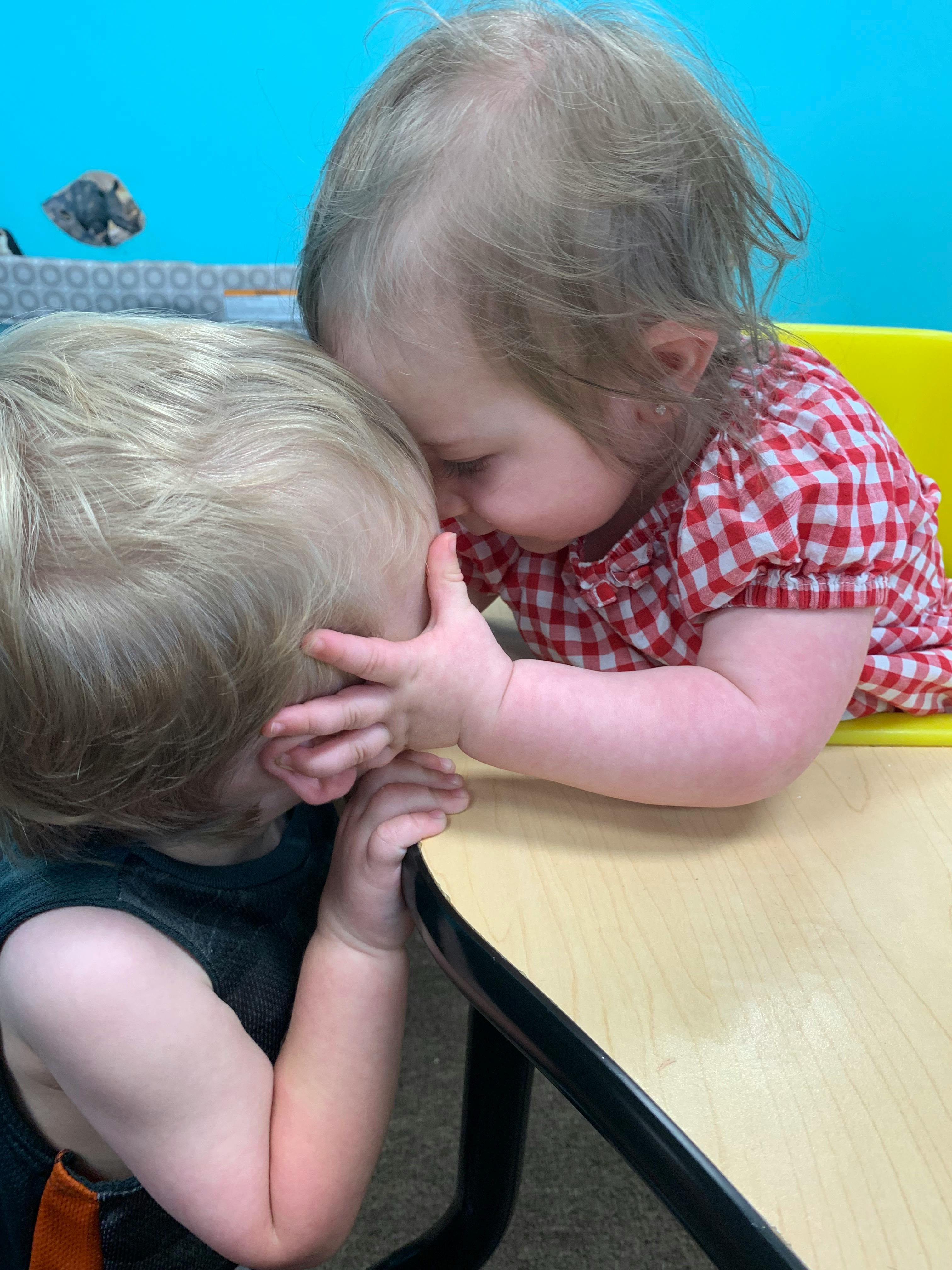 Two children with their heads together on a table