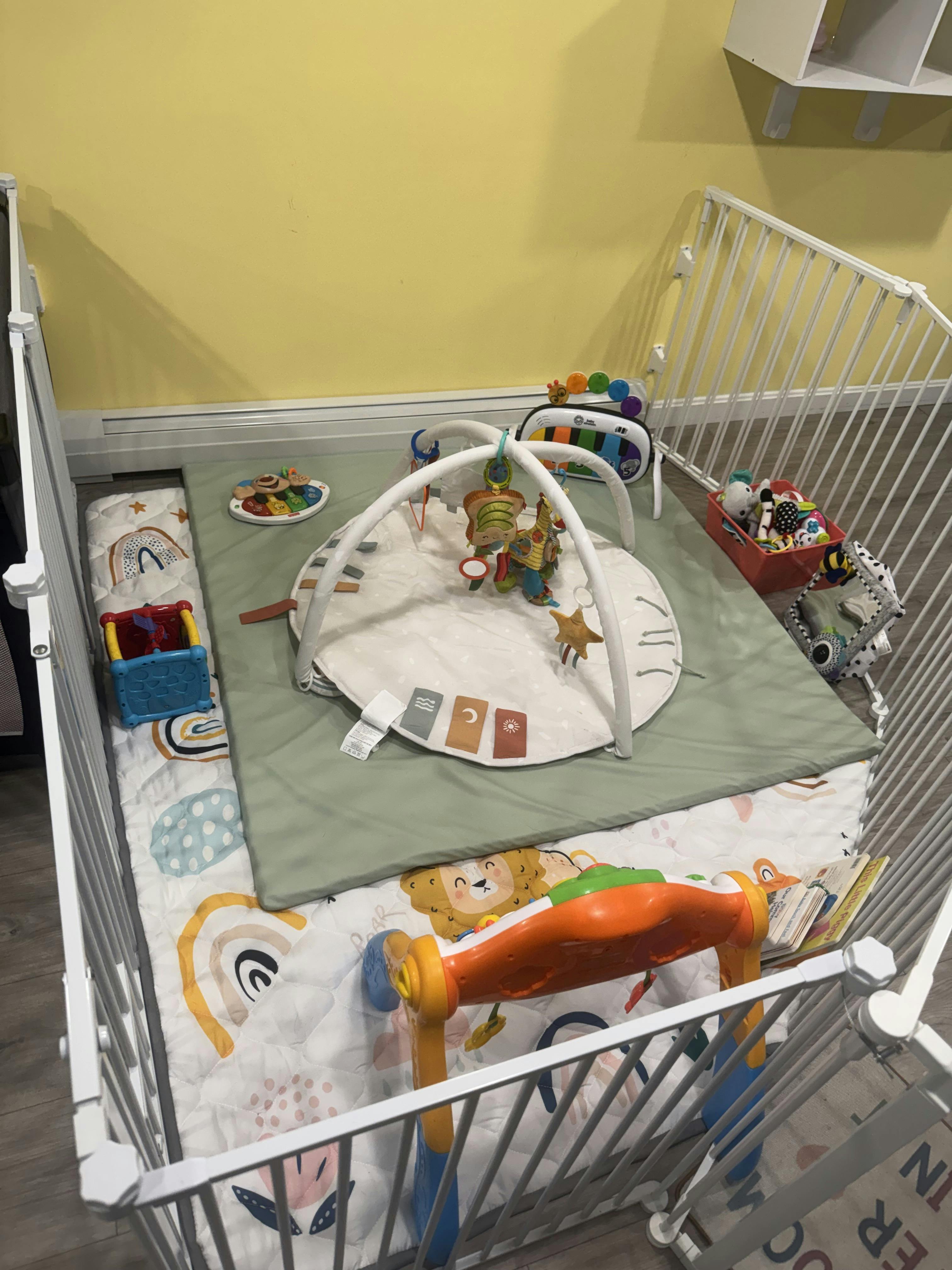 Baby playpen with play mat, activity gym, and various toys
