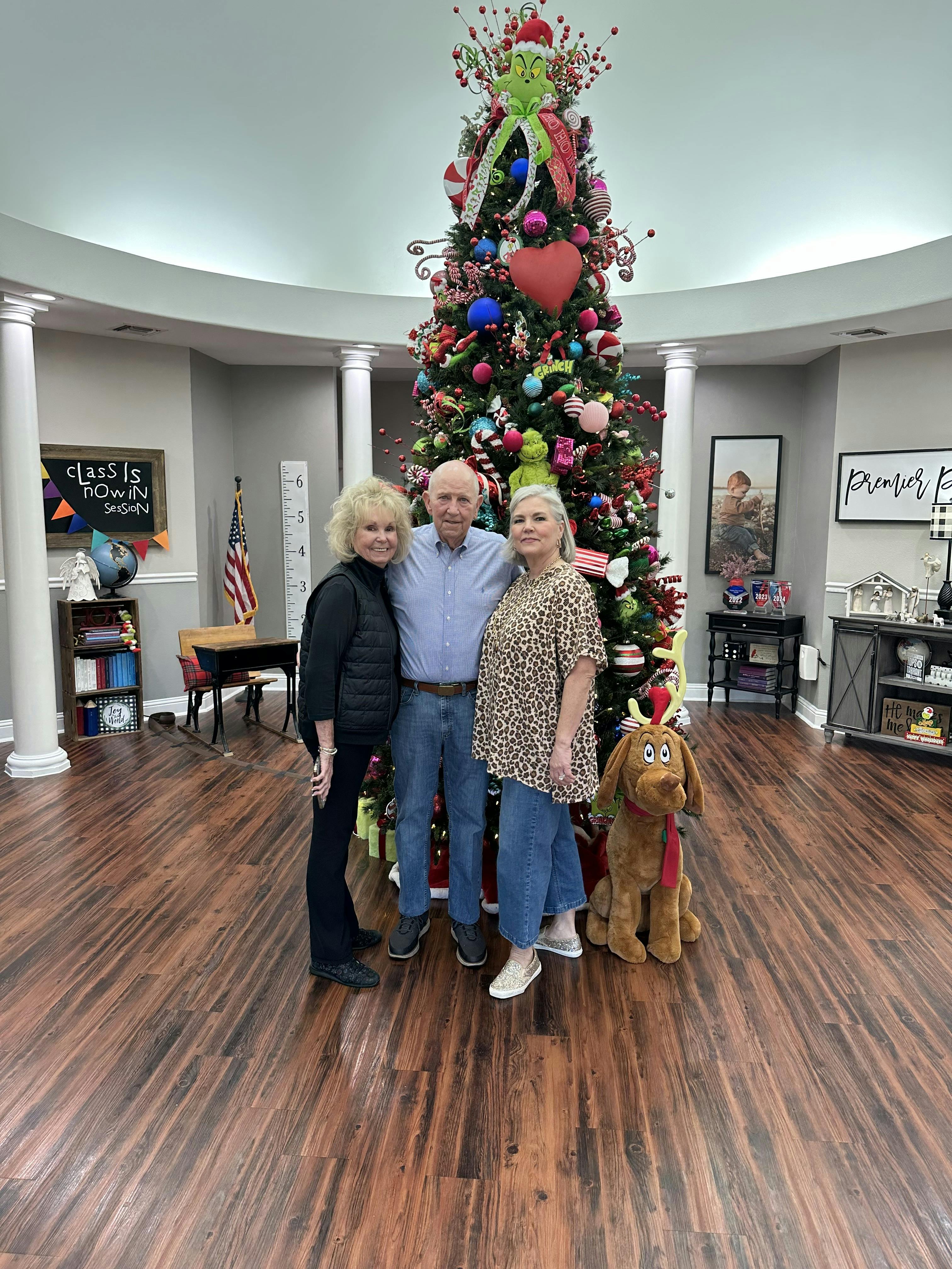 Three people posing in front of a heavily decorated Christmas tree