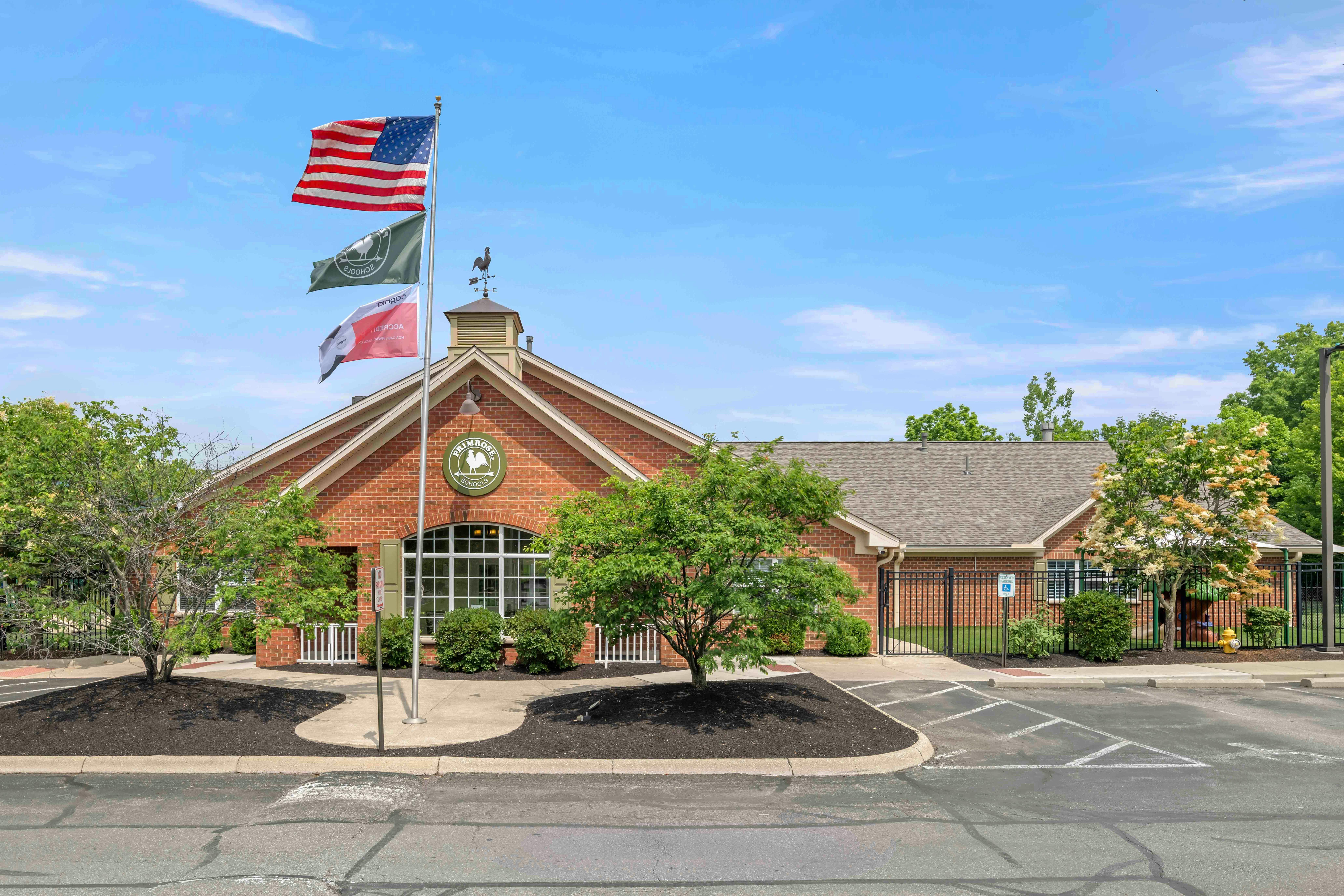 Brick building with a flagpole displaying an American flag and a rooster weathervane