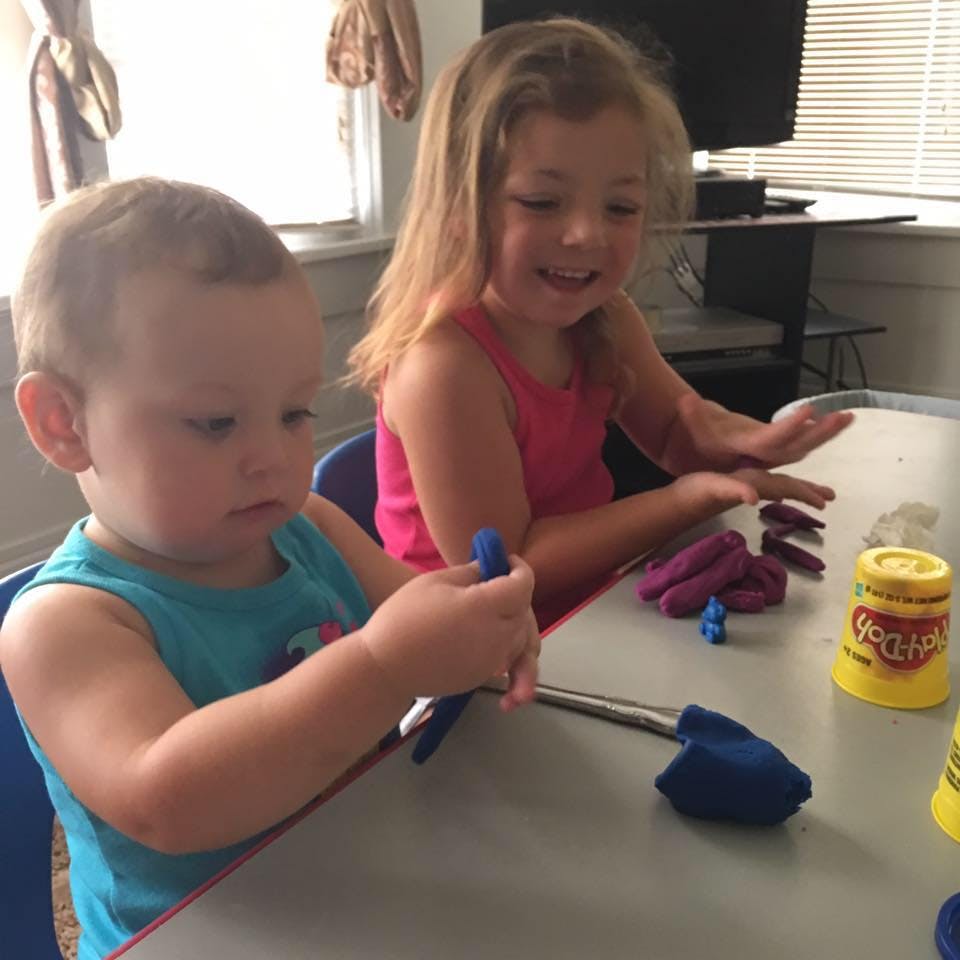 Two children playing with modeling clay at a table