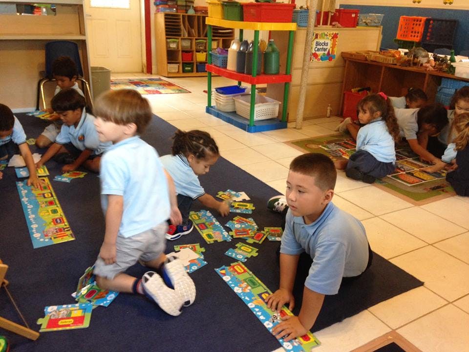 Children playing with puzzles on the floor in a classroom