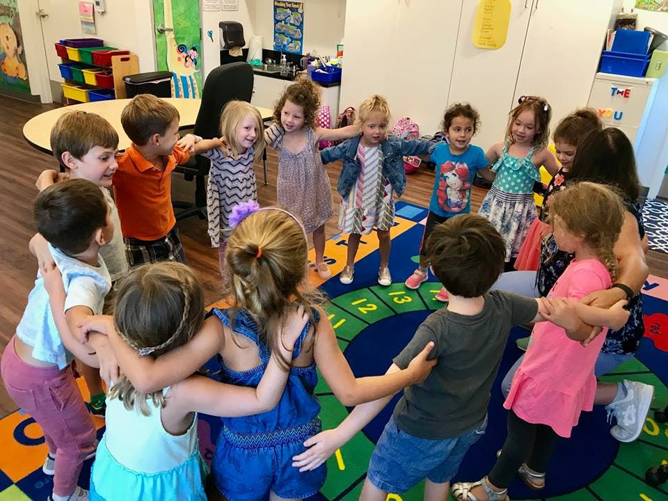 Group of children standing in a circle with arms around each other