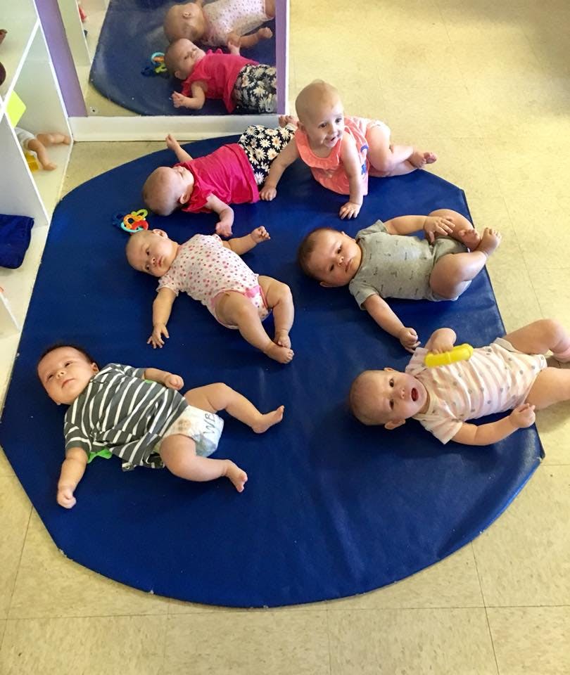 Multiple babies lying on a blue mat