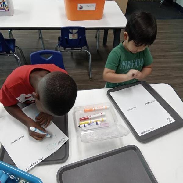 Two children drawing at a table in a classroom