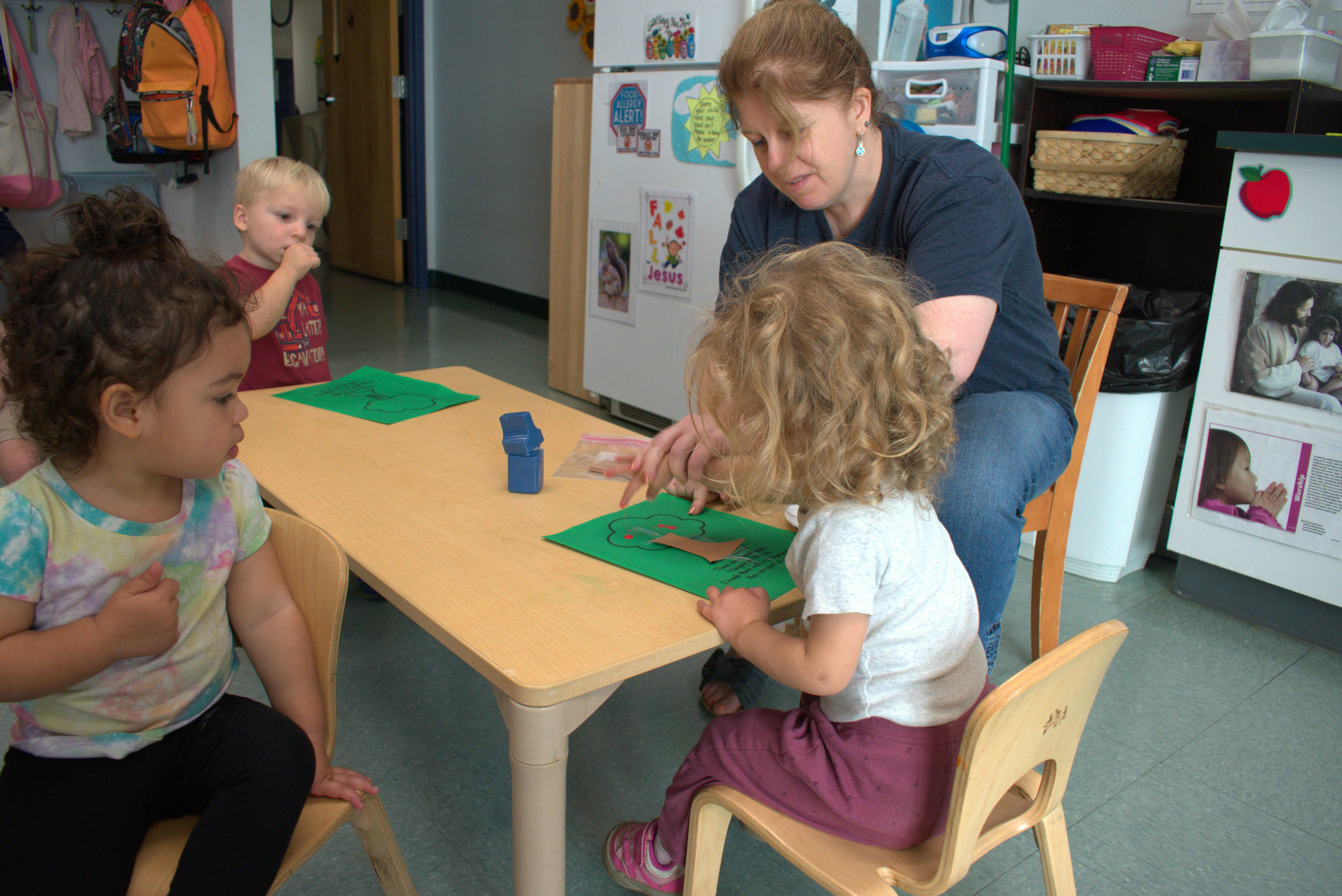 Adult and three children at a table with green paper
