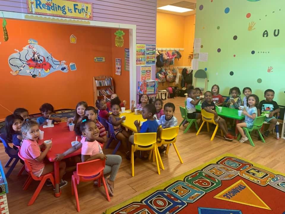 Children sitting at tables in a brightly colored classroom