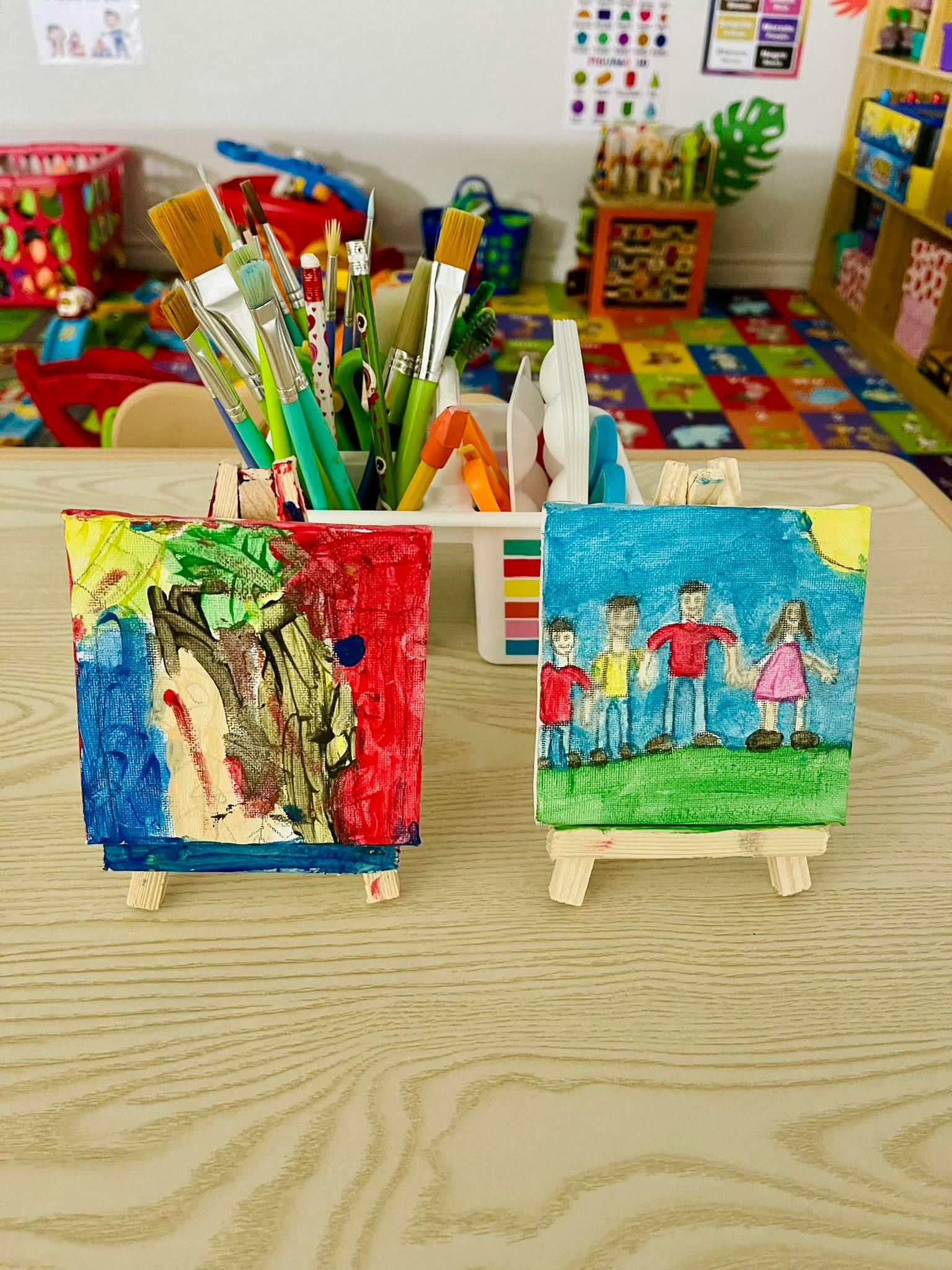 Two small paintings on easels, one abstract, one with stick figures