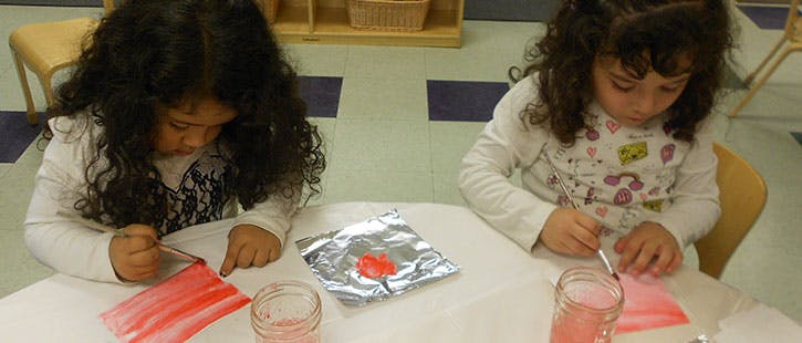 Two children painting at a table
