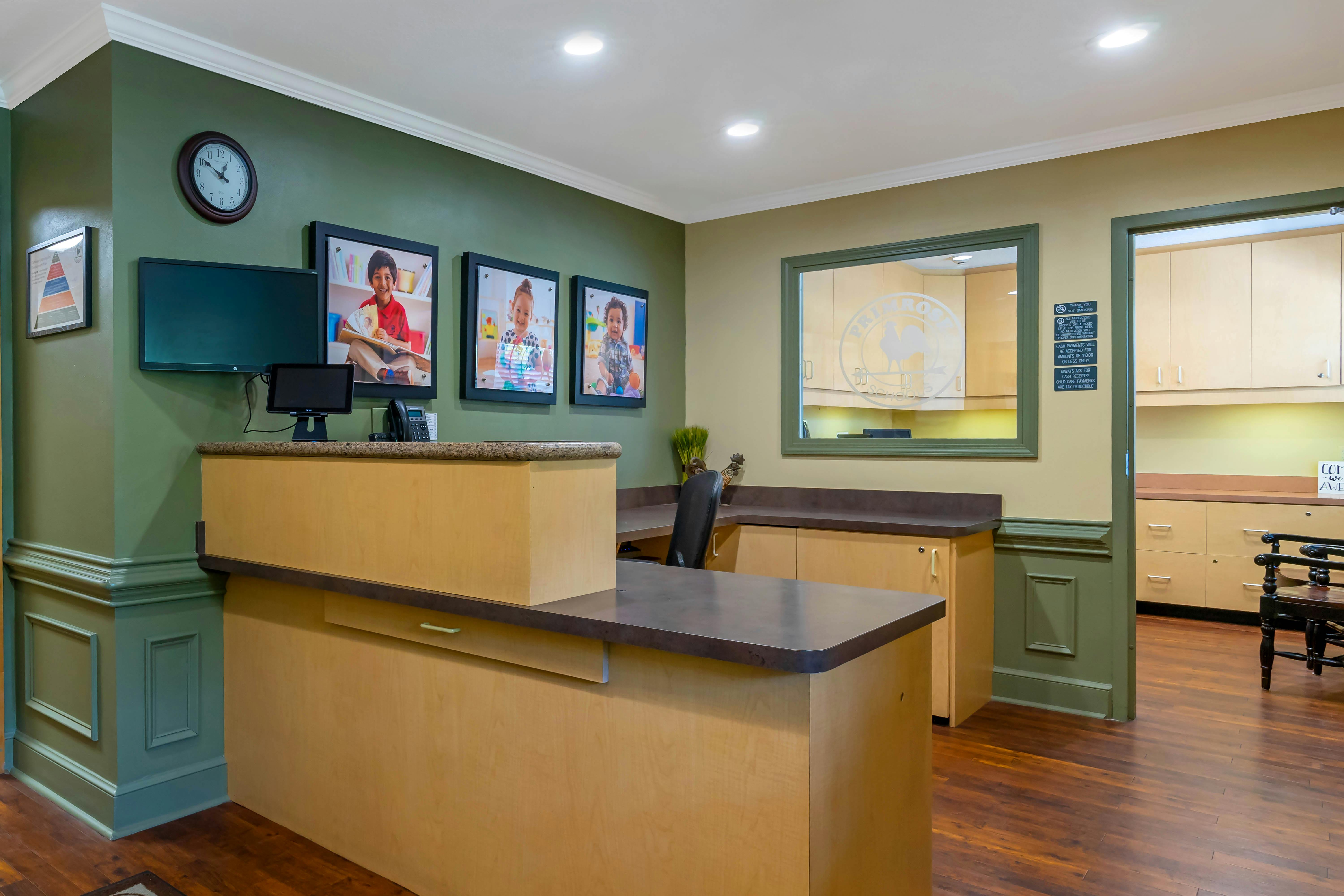 Reception desk with three framed photos of children and two computer monitors
