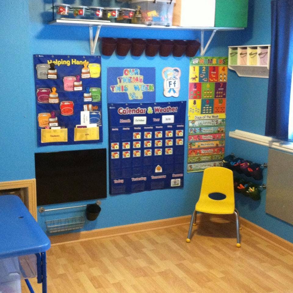 Classroom wall with calendar, charts, and a yellow chair