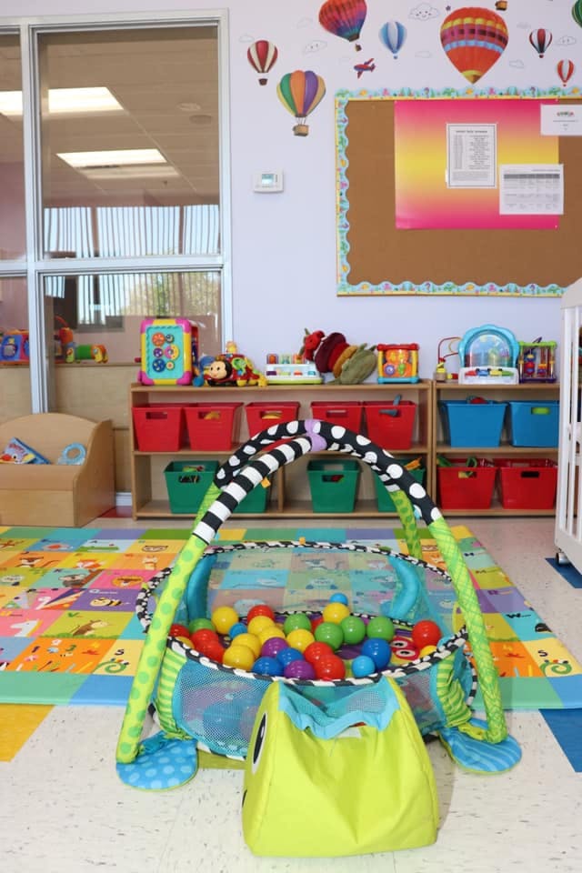 Play area with a ball pit, colorful mat, and shelves of toys