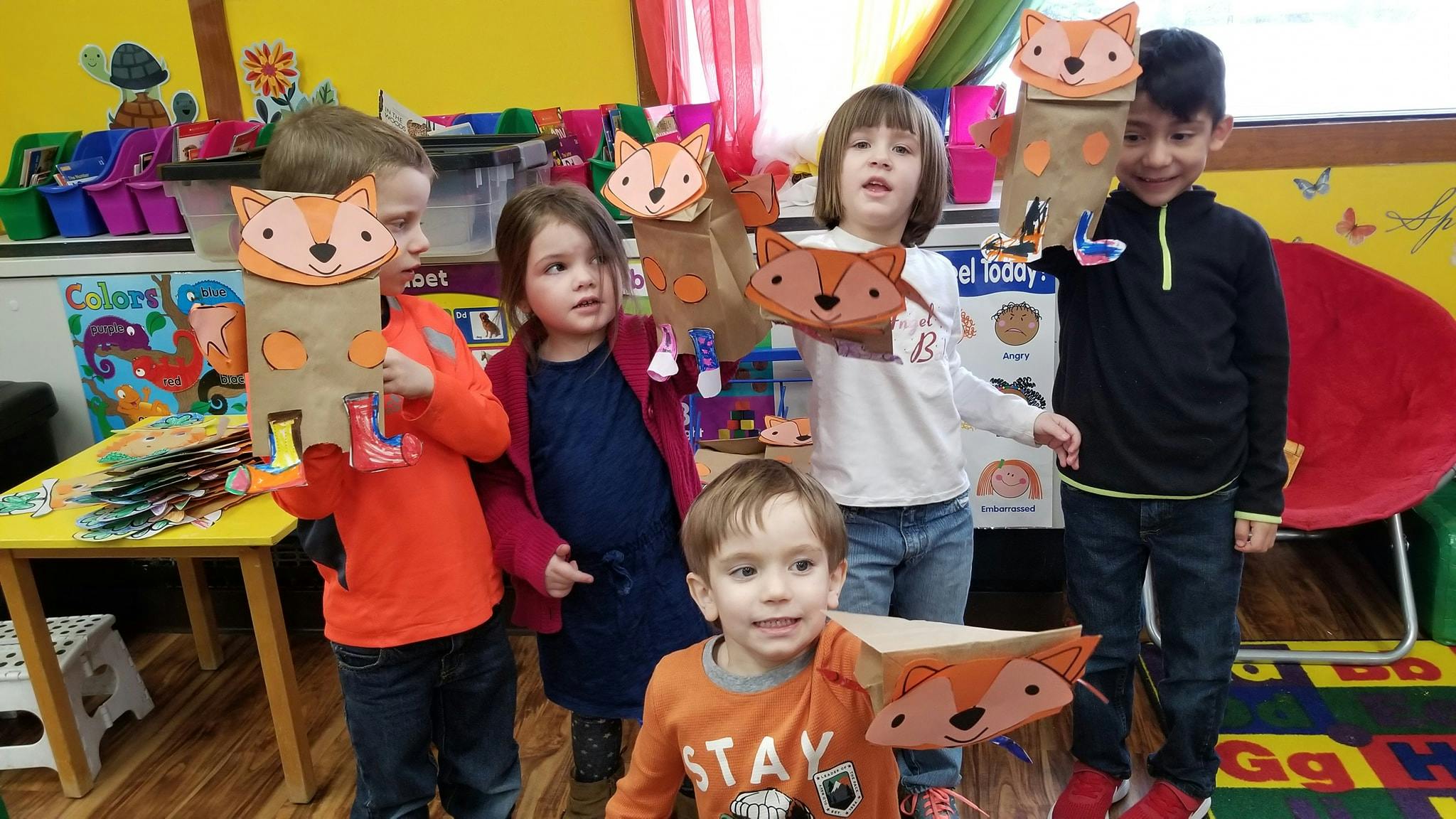 Children holding fox puppets in a classroom