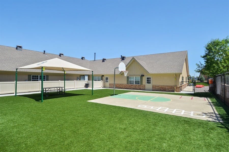 Outdoor play area with a basketball court and a shaded picnic table