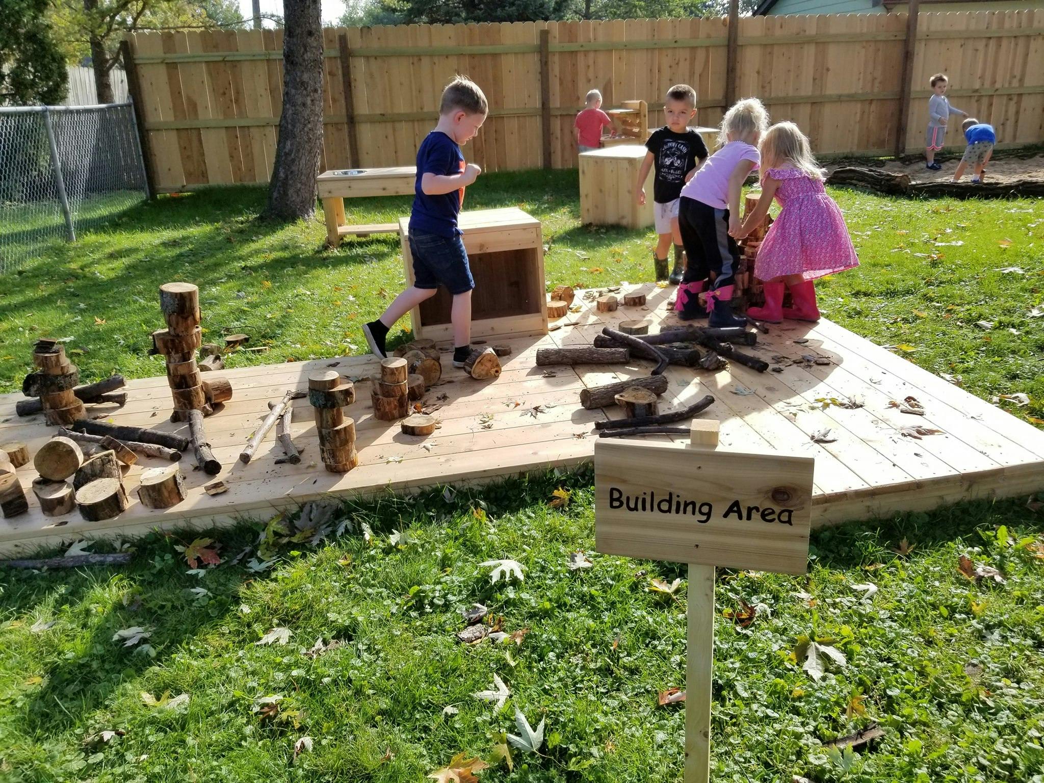 Children playing with wood pieces in a building area