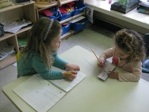 Two children writing at a table