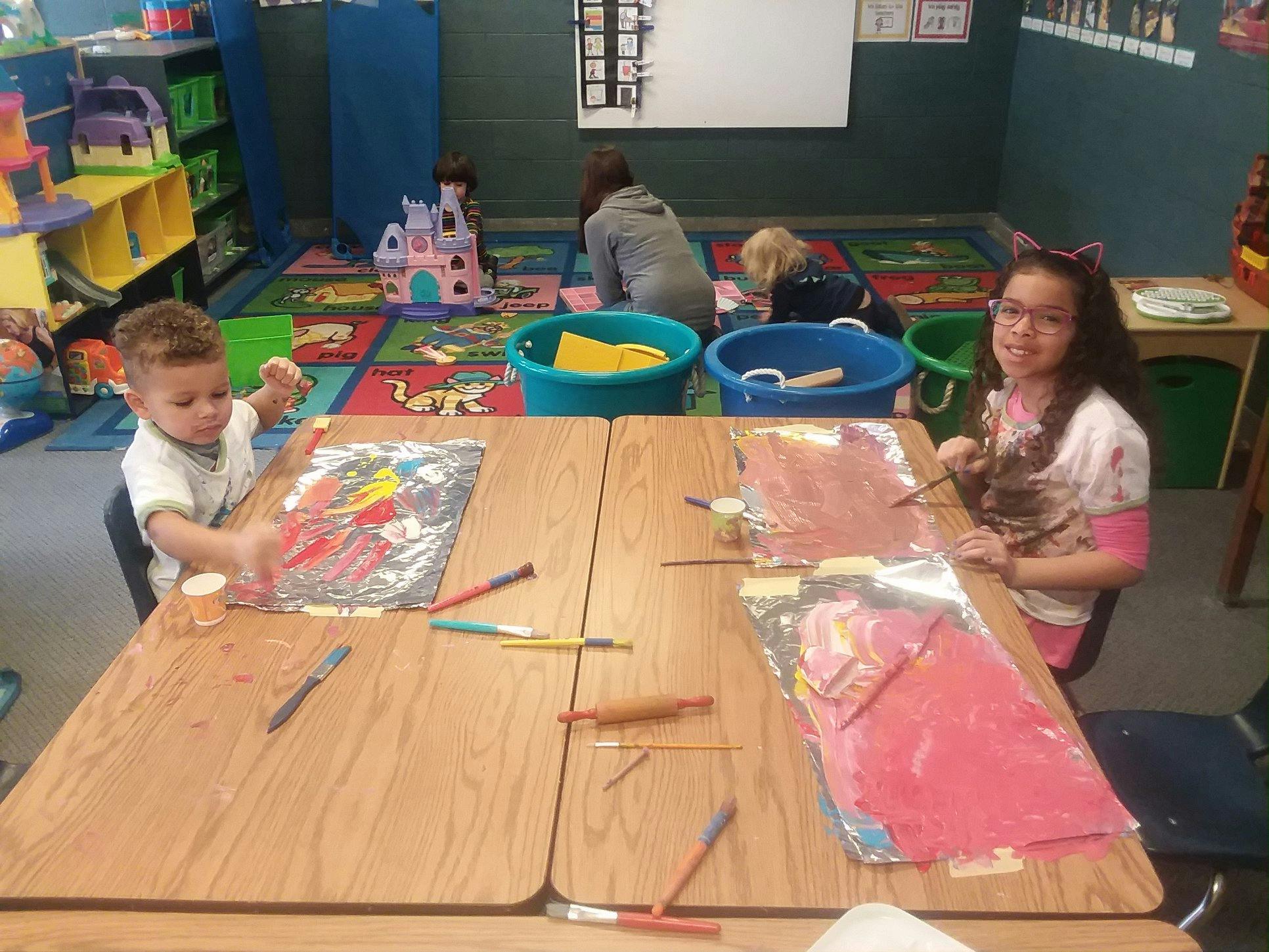 Two children painting at a table in a classroom