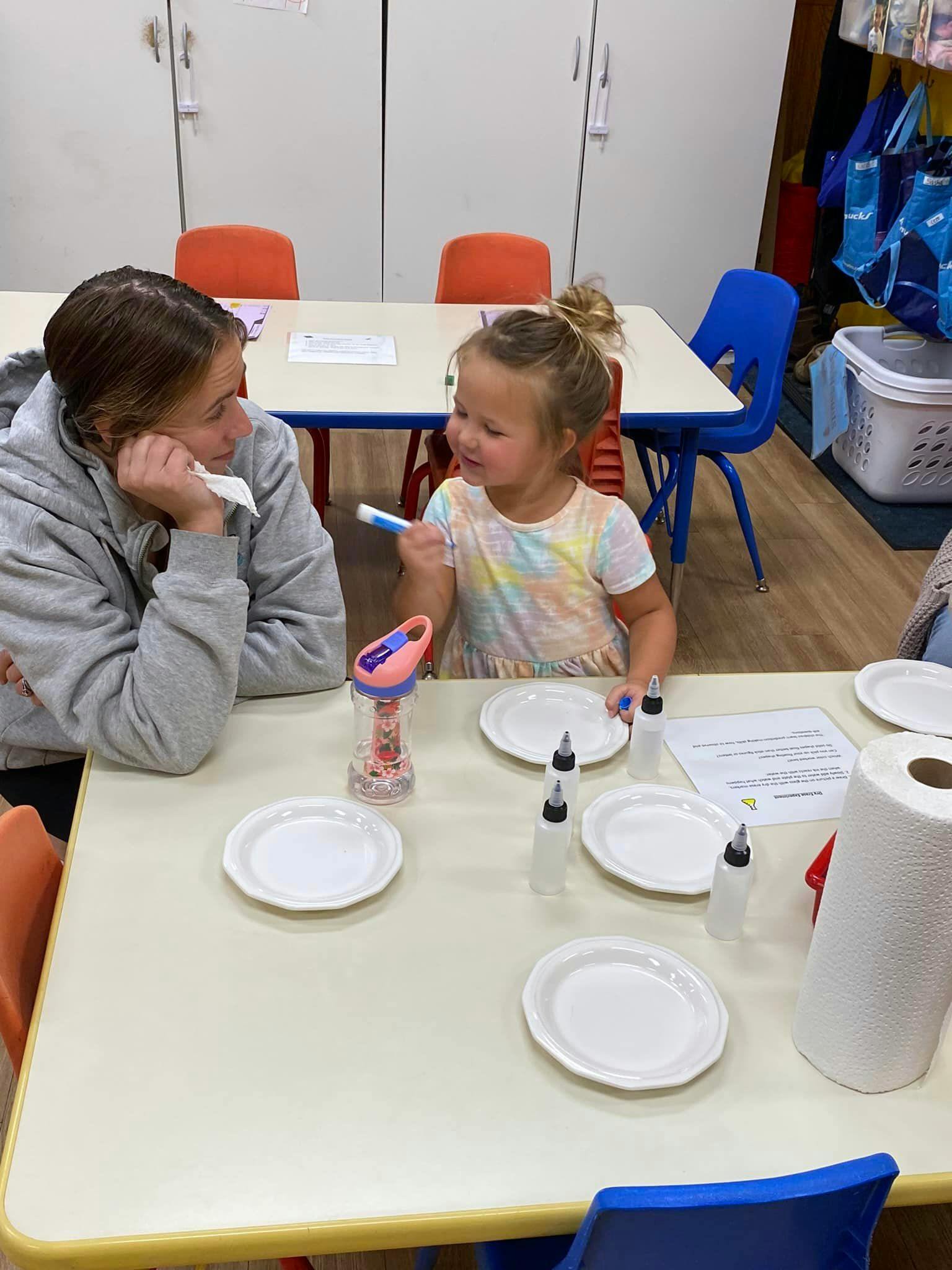 Person and child at a table with plates and craft supplies