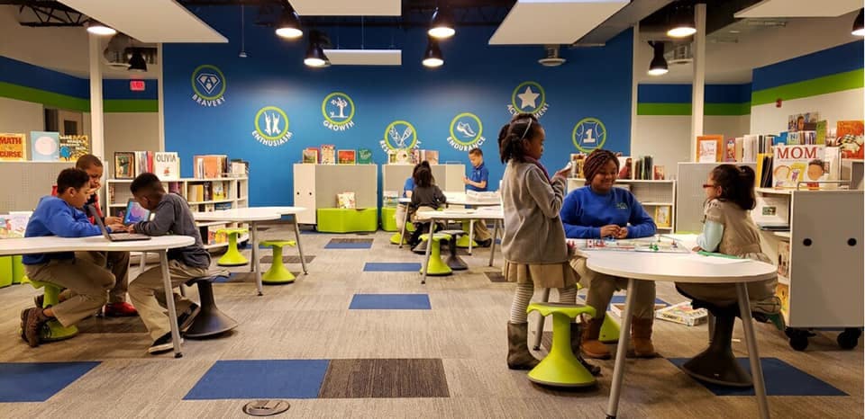 Children and adults in a classroom with tables and chairs