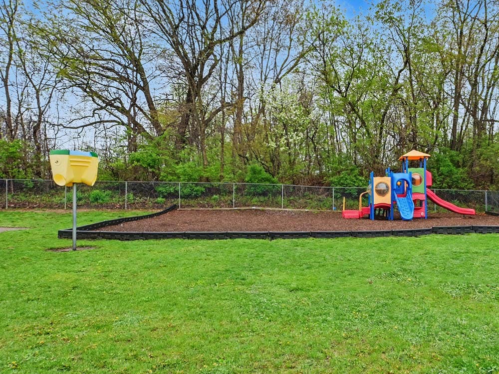 Children's playground with slides and swings on wood chips next to a grassy area