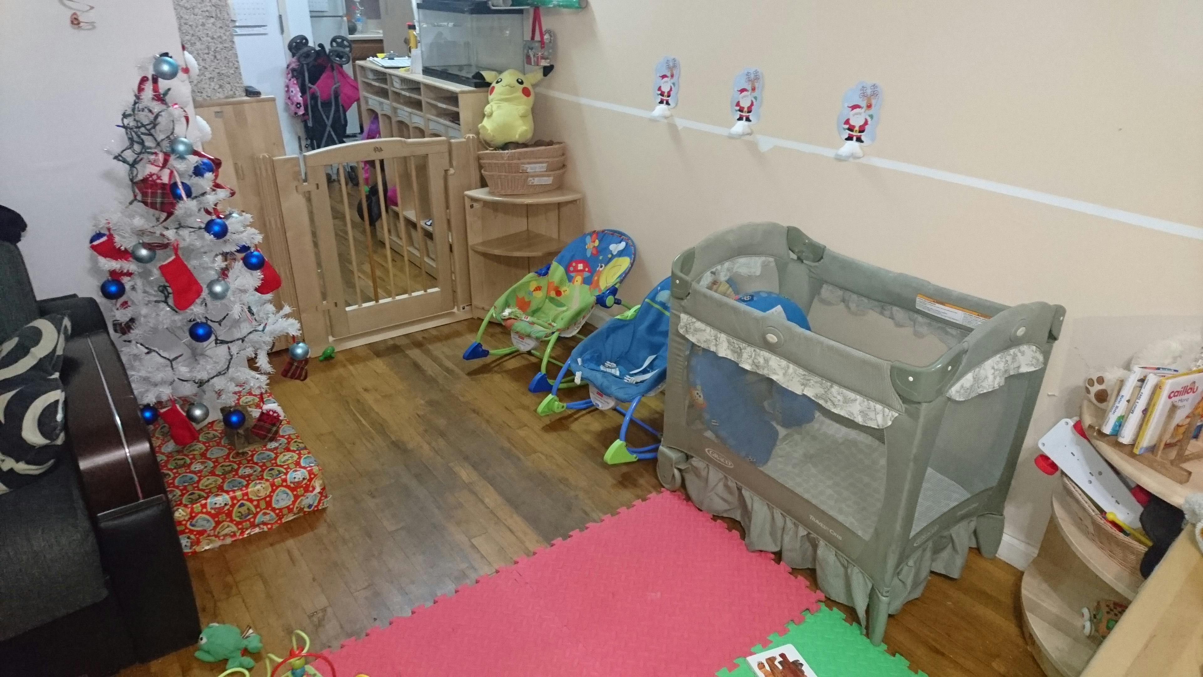 Nursery room with a crib, baby bouncers, and a decorated Christmas tree