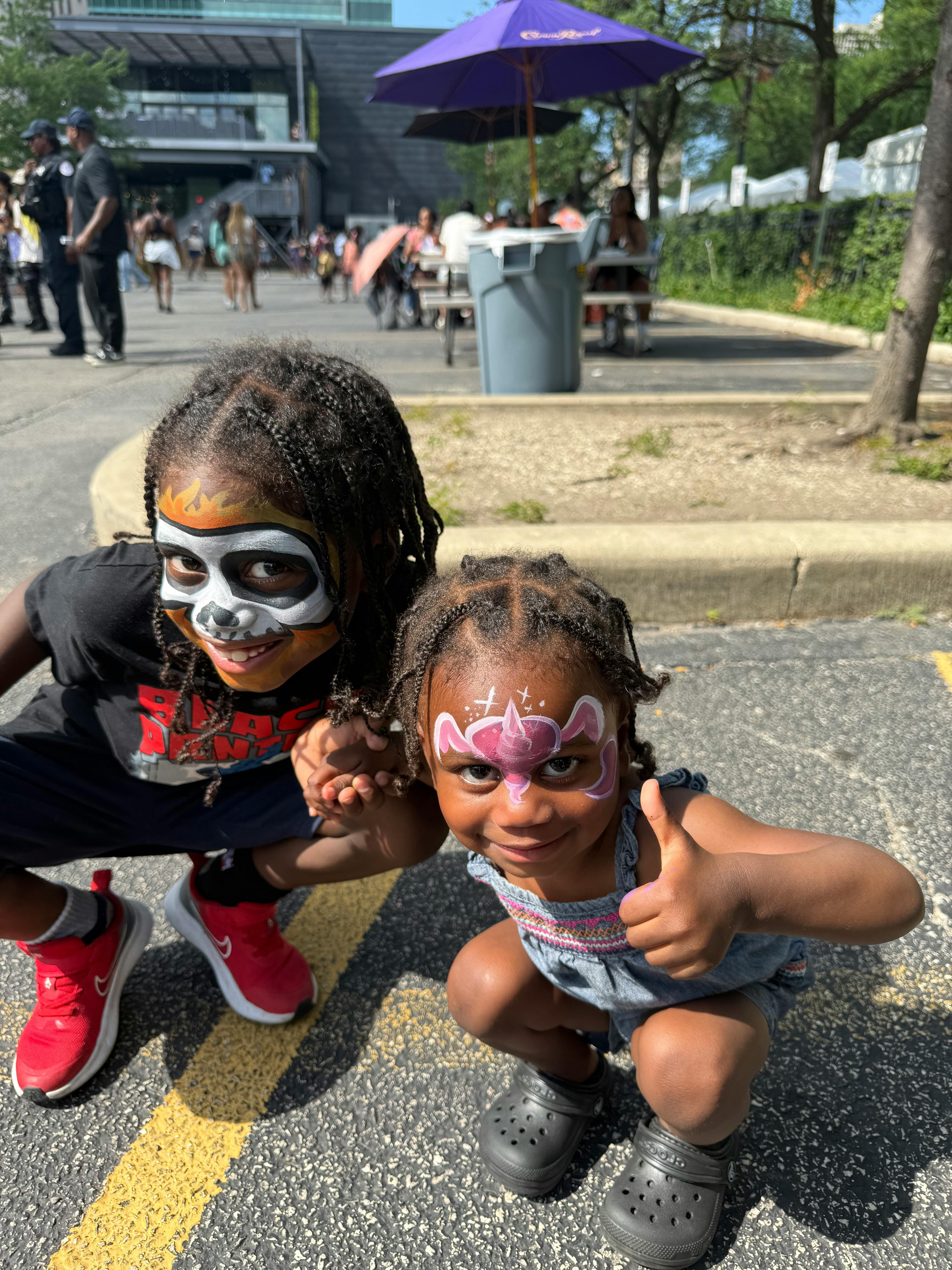 Two children with face paint crouching outdoors