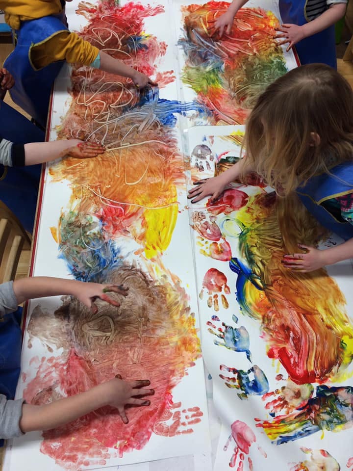 Children finger painting on a large sheet of paper