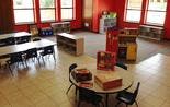 Empty classroom with tables, chairs, and shelves