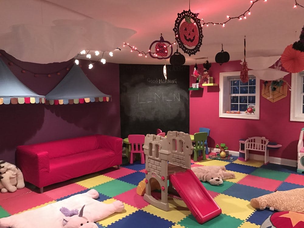 Playroom with colorful floor mats, a red couch, and a small slide