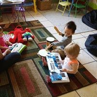 Two children playing with musical instruments on a rug