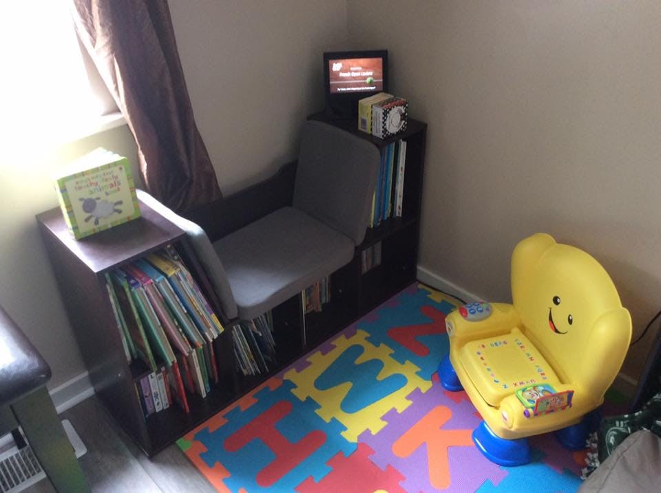 Child's reading nook with small chairs, books, and alphabet mat
