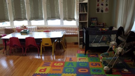 Children's play area with small table and chairs, crib, and alphabet mat