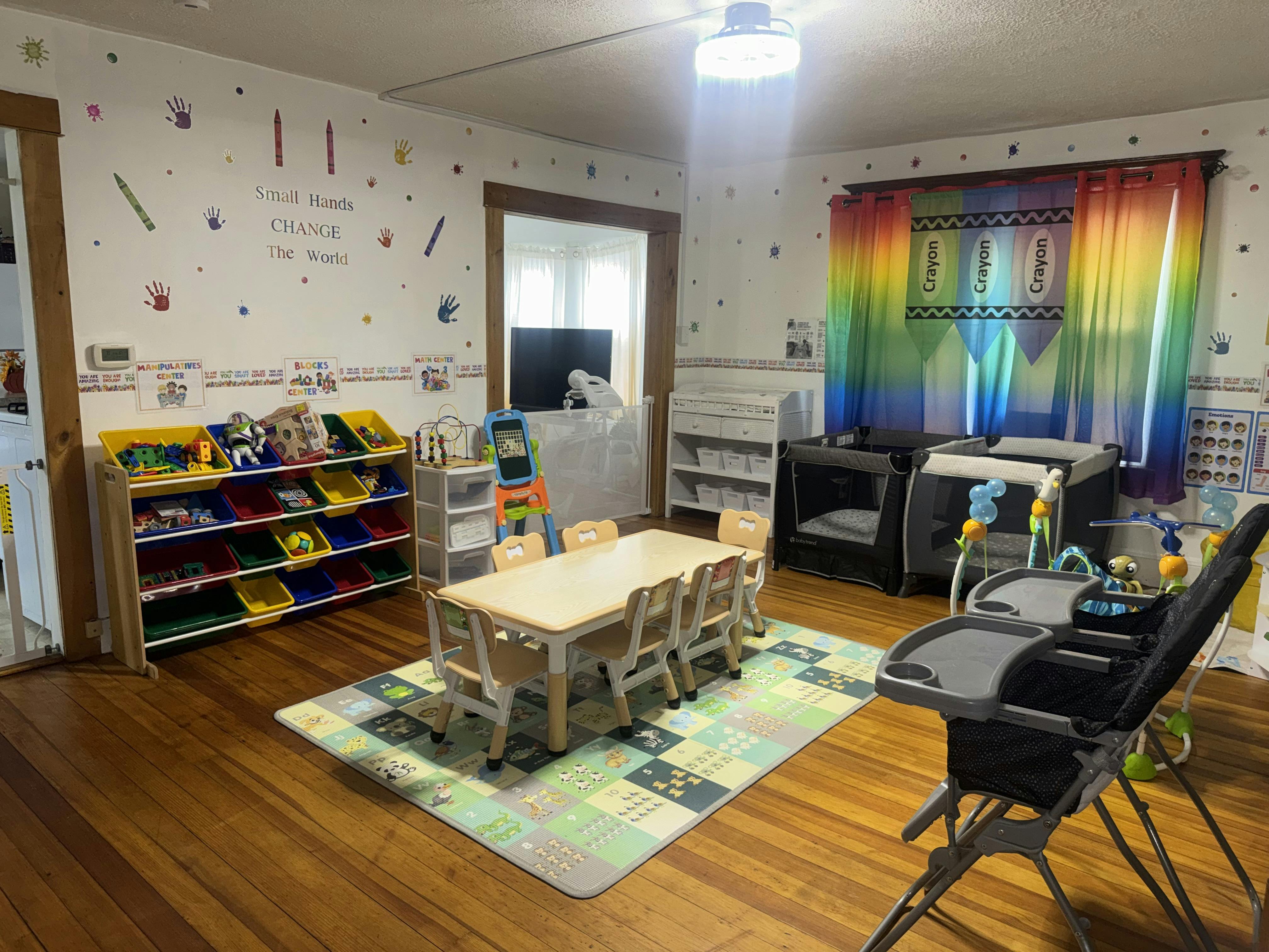 Children's classroom with small table and chairs, toy shelves, and playards
