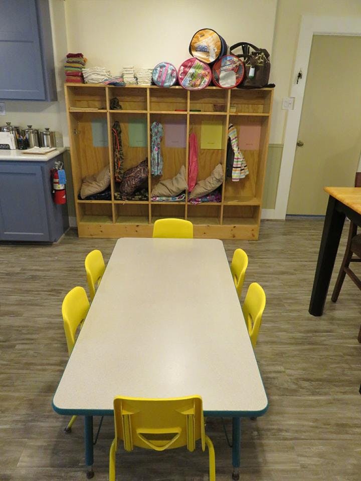 Classroom with a table and chairs, and cubbies with items