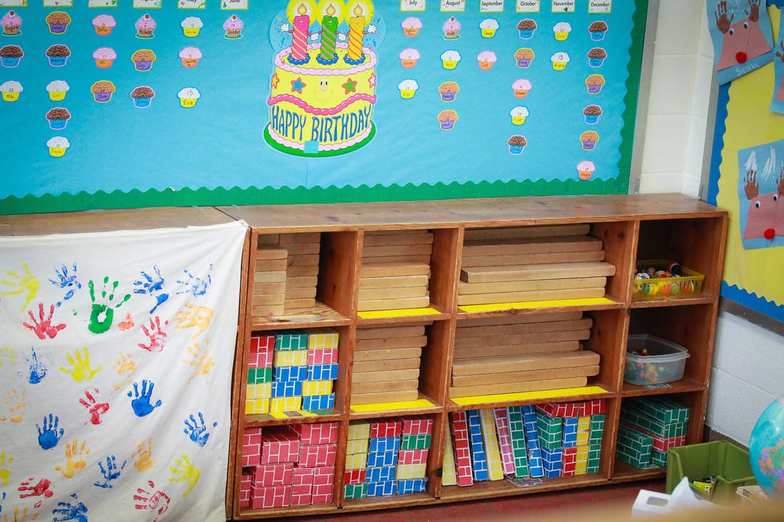 Classroom with a wooden shelf unit and a birthday bulletin board