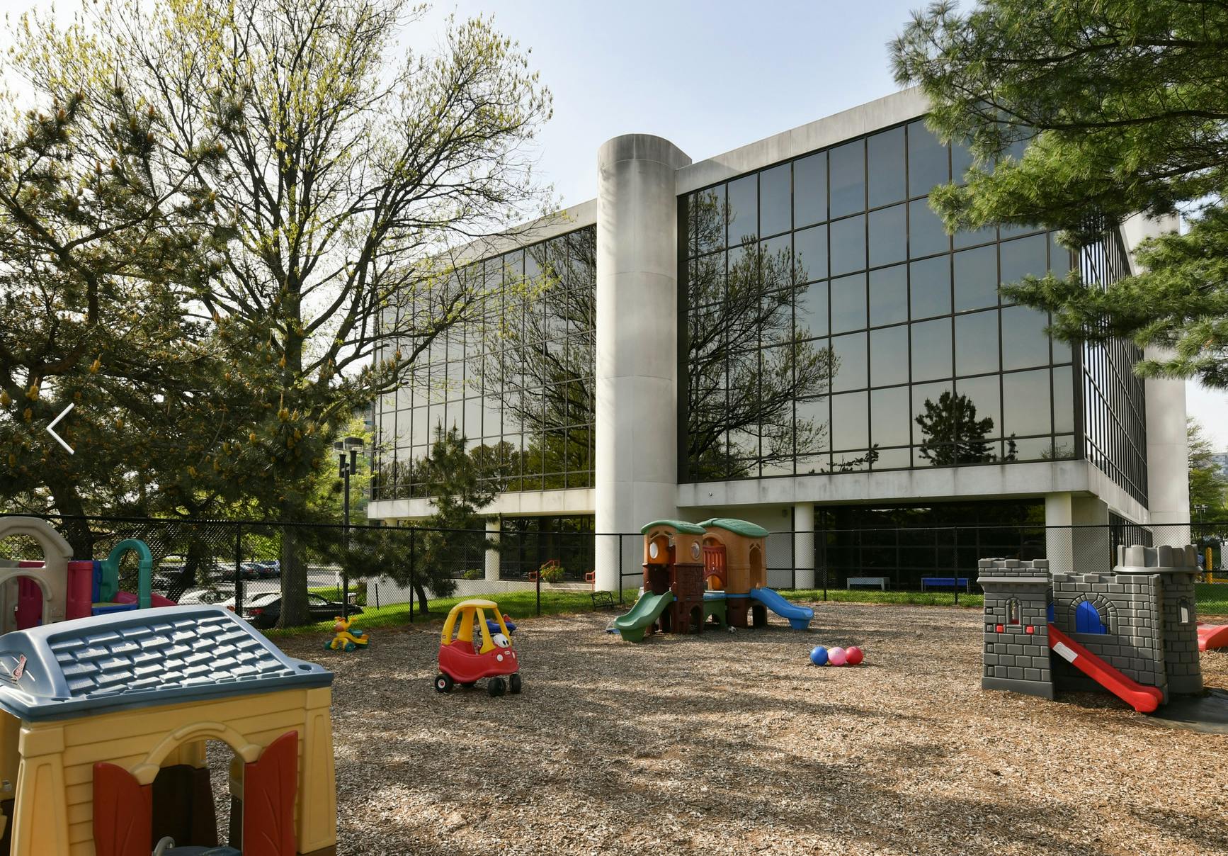 Playground with playhouses and slides in front of a large building