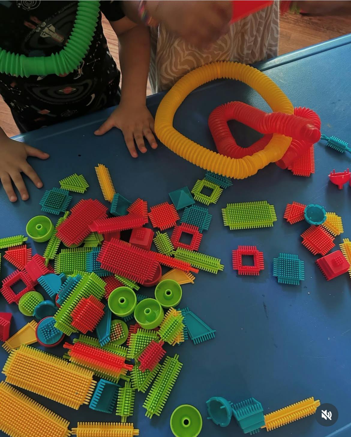 Child's hands on a table with colorful building toys