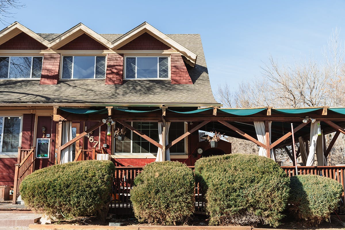 Red building with multiple dormers and a covered outdoor patio