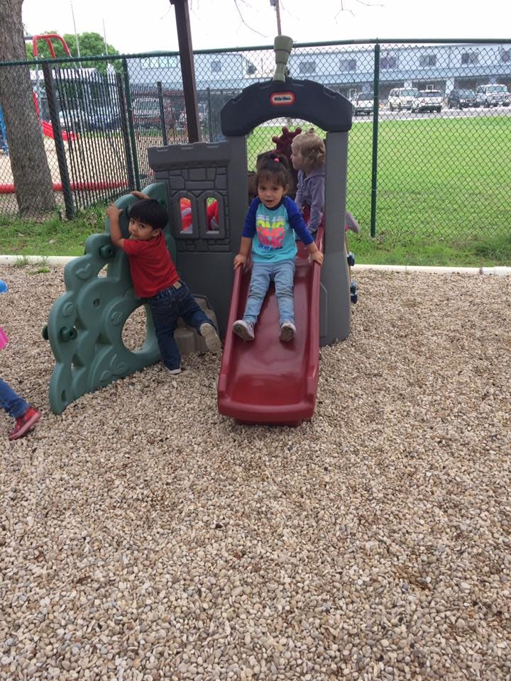 Two children playing on a slide and climbing structure on a playground