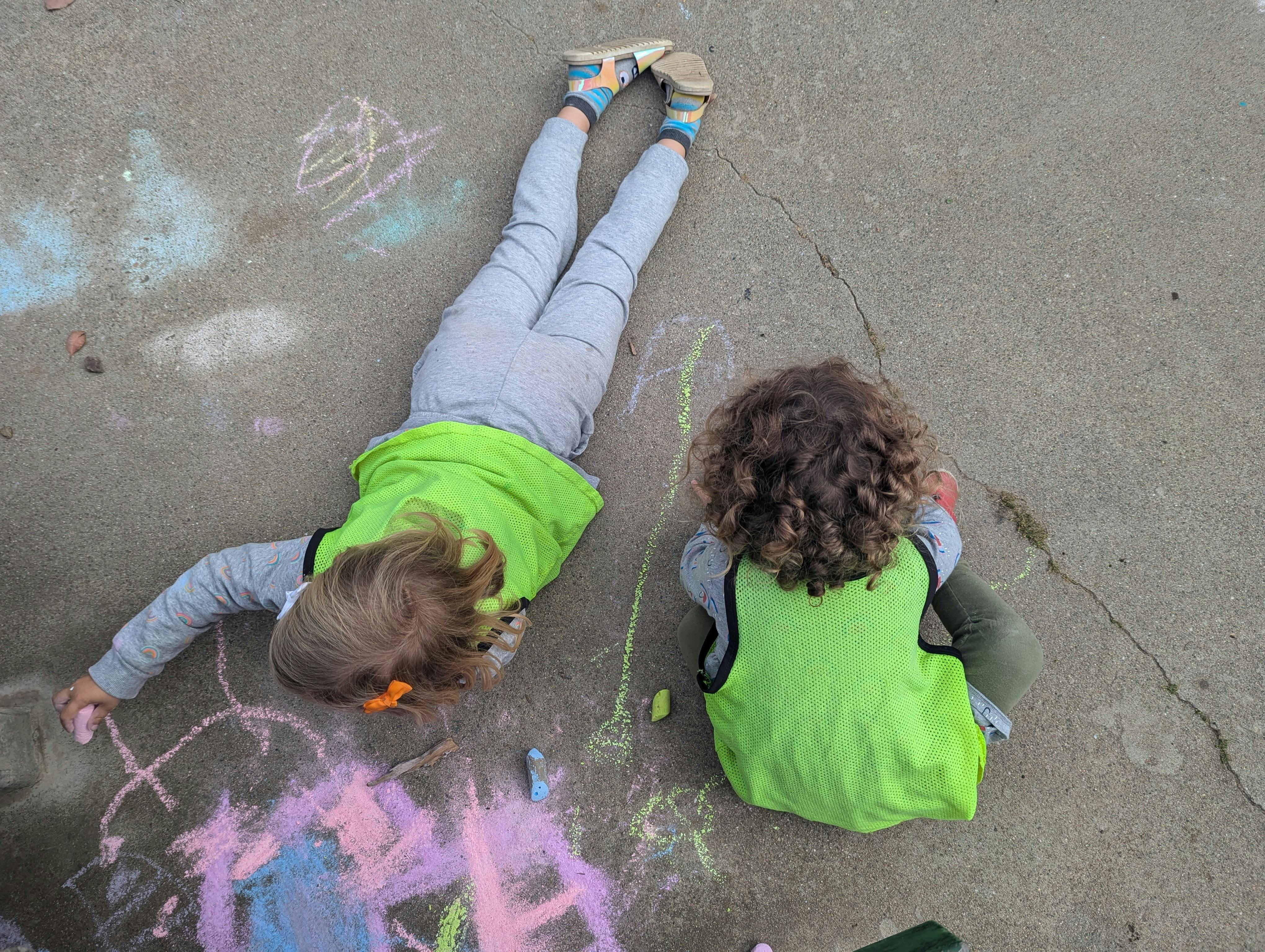 Two children drawing with chalk on pavement