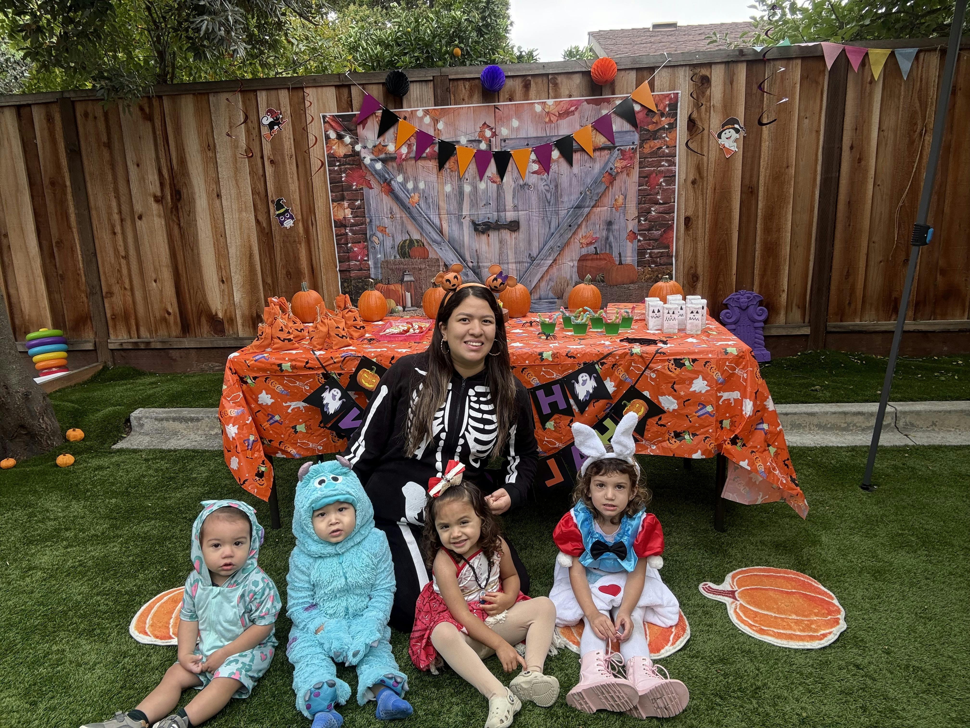 Person in skeleton costume with four children in costumes at a Halloween party