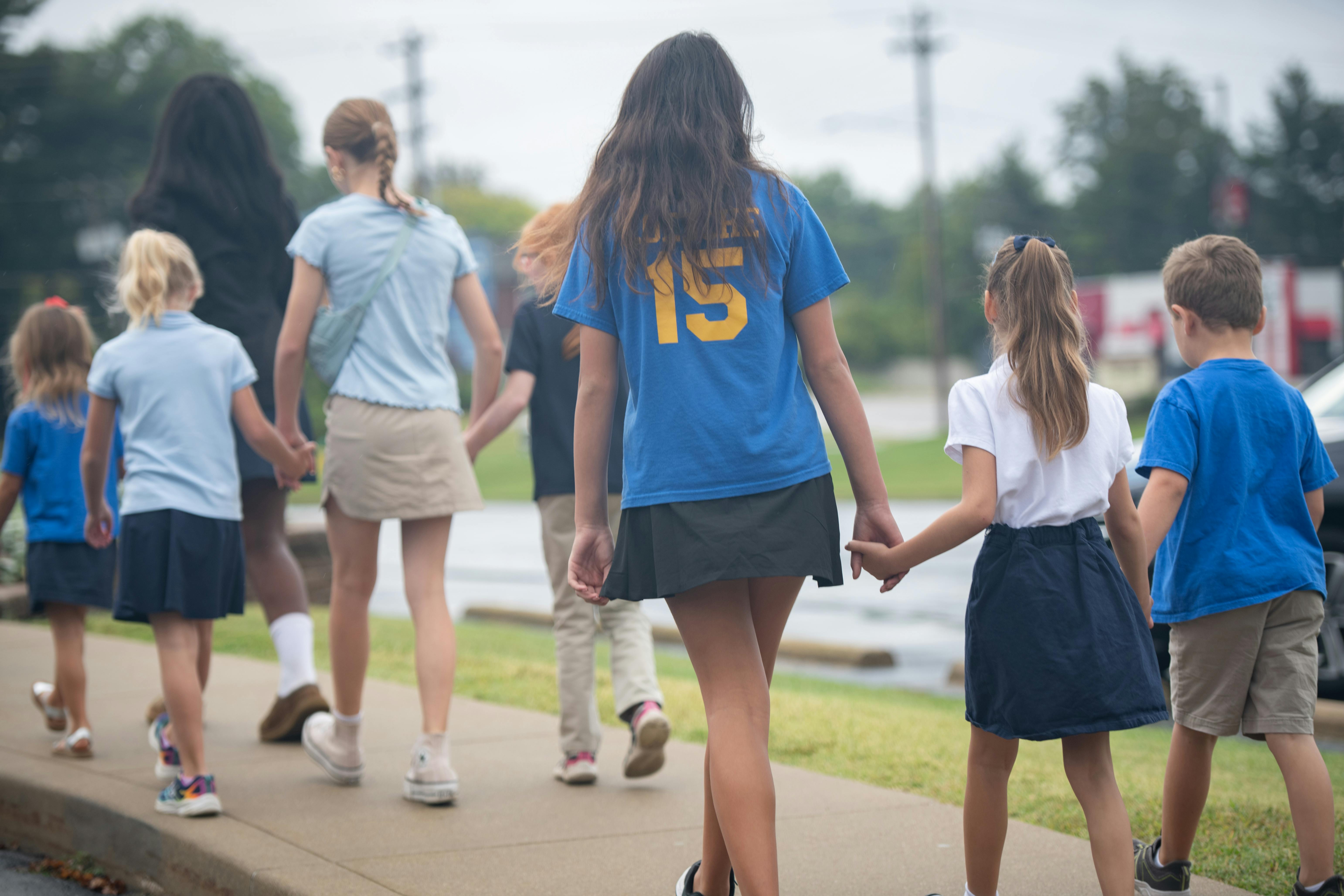 Group of children walking away on a sidewalk, some holding hands