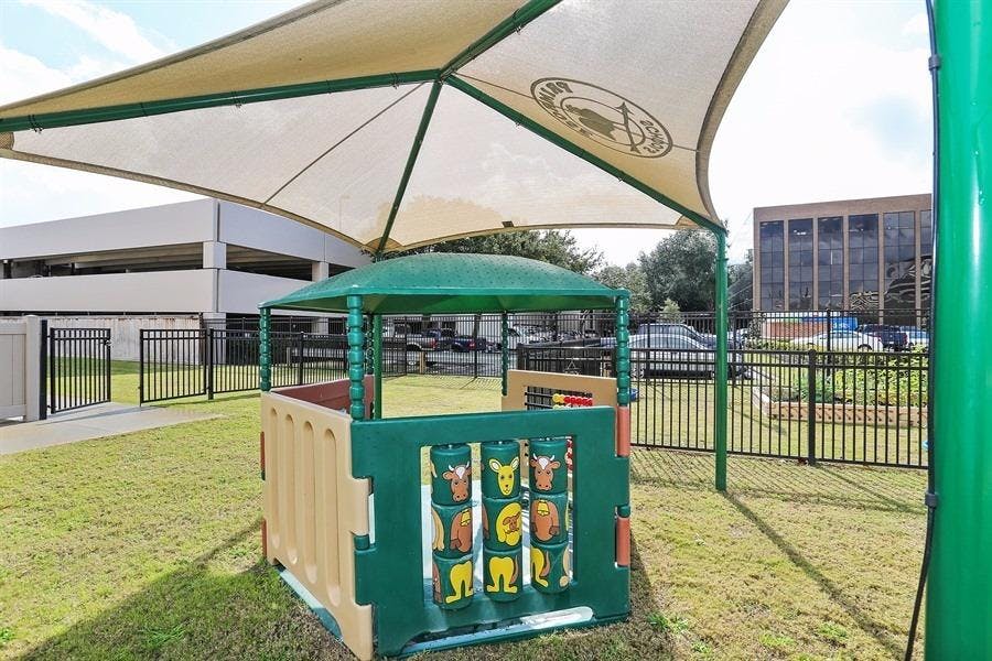 Play structure with a green roof and a large shade canopy over a grassy area