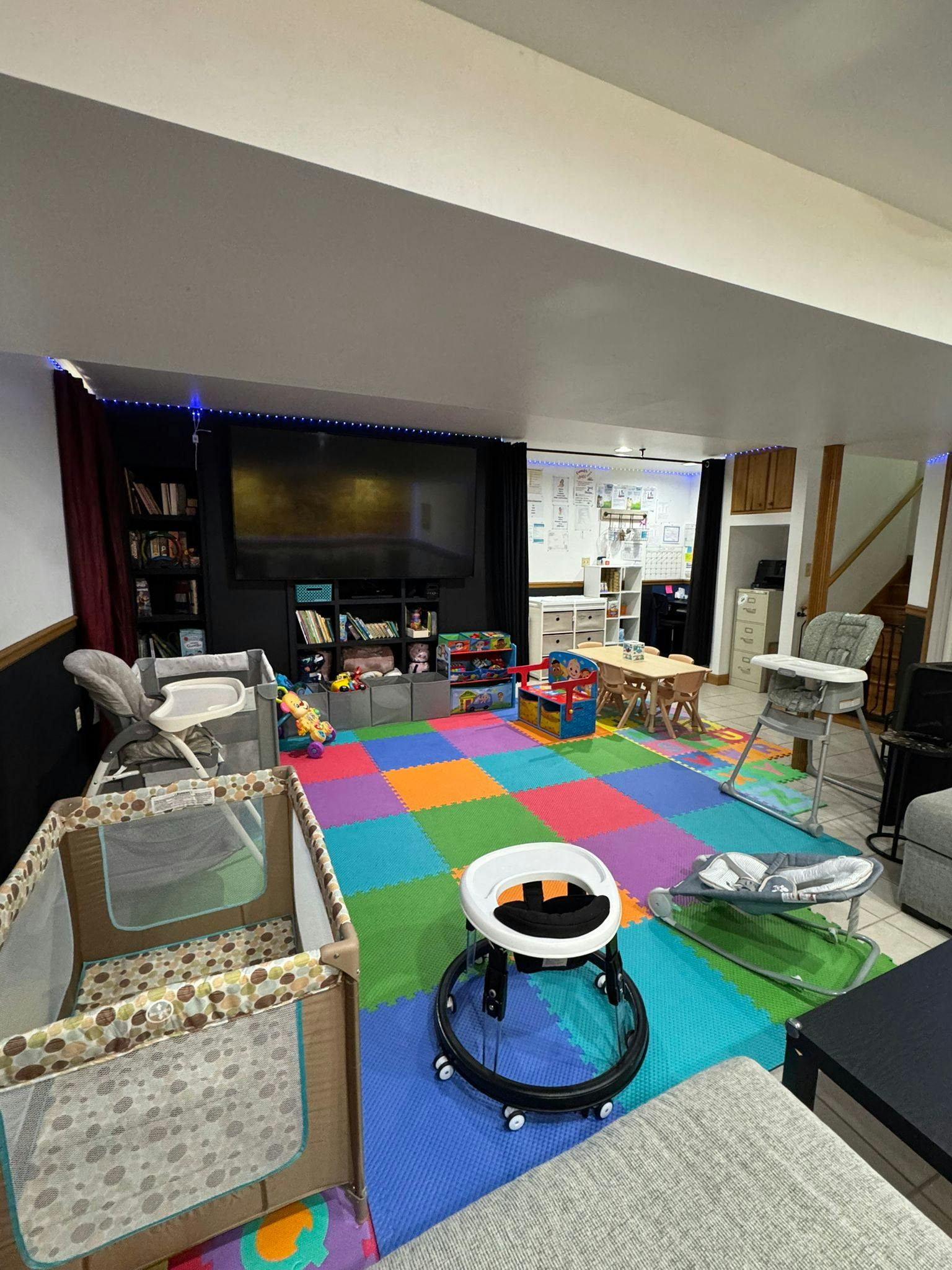Playroom with colorful floor mats, cribs, and baby equipment