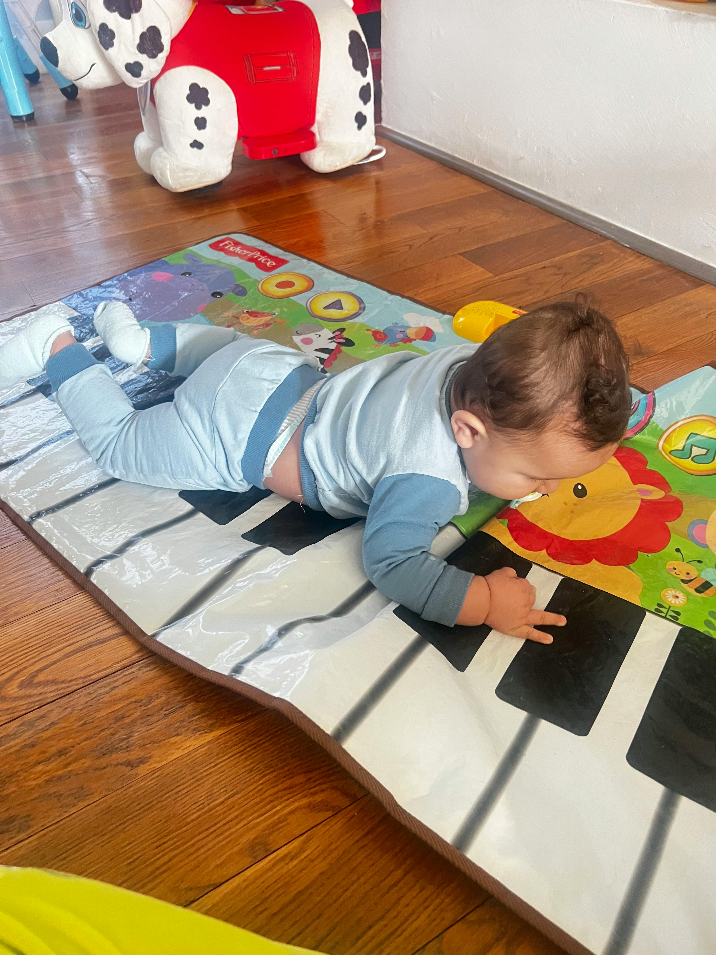 Child on stomach playing with a piano mat